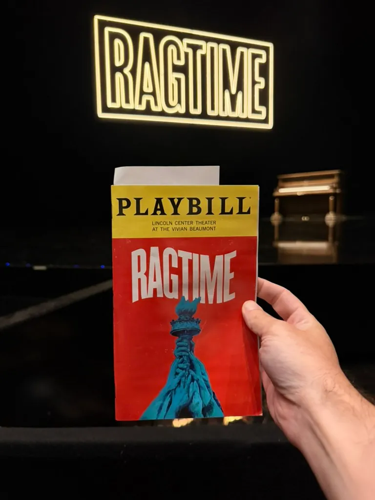 Ragtime Playbill held up in front of the stage under a glowing Ragtime sign