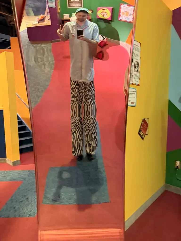 Keith taking a mirror selfie in a funhouse mirror that stretches his checkered pants extremely long
